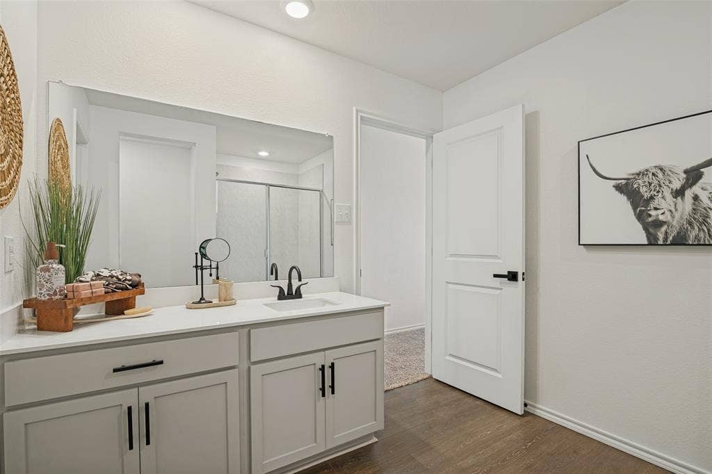 1506 Buckaroo Lane, Josephine, TX 75189 Bathroom featuring a vanity with light gray cabinetry, white countertop, integrated rectangular sink, matte black hardware, and an expansive wall-mounted mirror