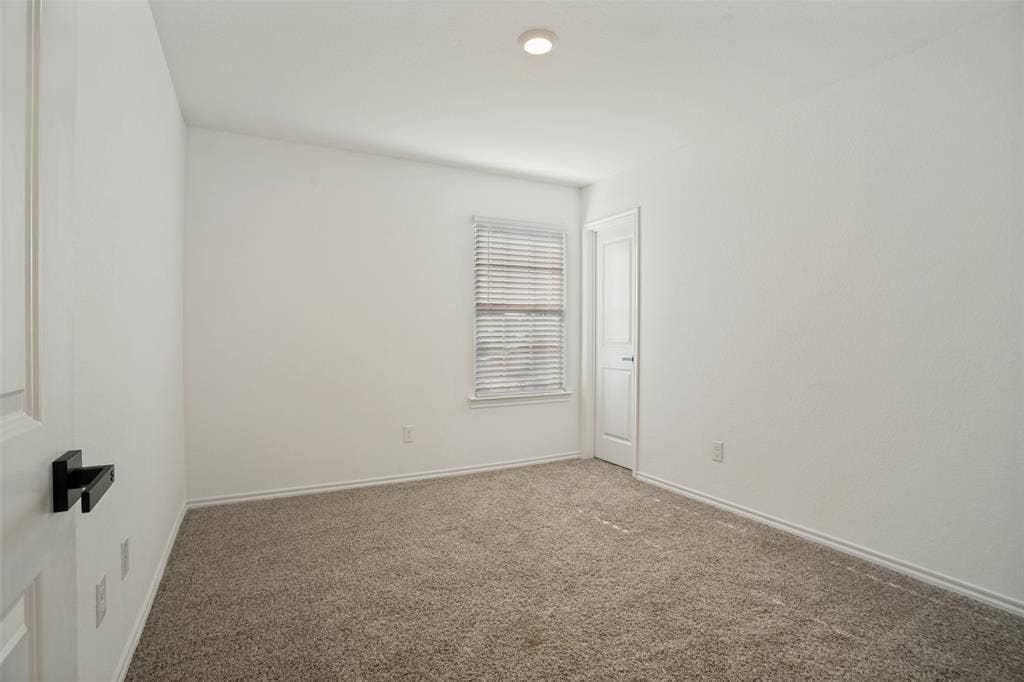 1506 Buckaroo Lane, Josephine, TX 75189 Neutral-toned carpeted flooring, single-panel interior door with a matte black lever handle, recessed ceiling lighting, and window with adjustable horizontal blinds