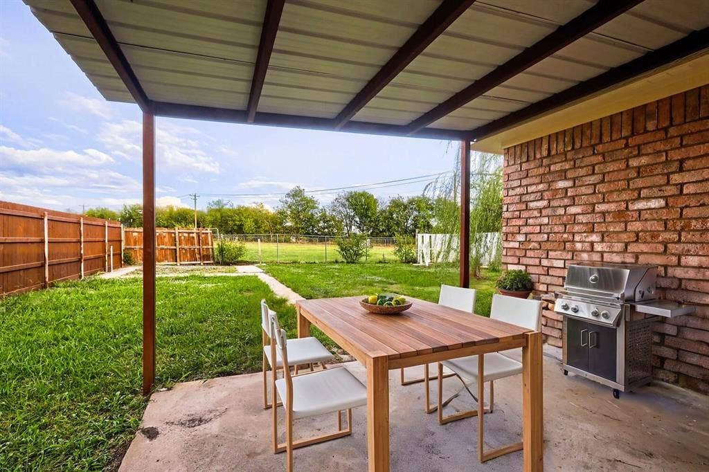 112 Sebastian Lane, Josephine, TX 75173 Covered patio featuring a concrete slab, exposed brick exterior wall, and metal roof structure overlooking a fenced backyard