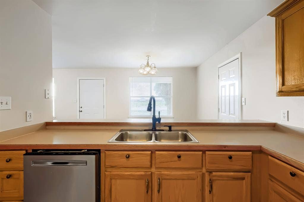 112 Sebastian Lane, Josephine, TX 75173 Kitchen featuring wood cabinetry, stainless steel dishwasher space, dual-basin sink, matte black gooseneck faucet, and solid-surface countertop