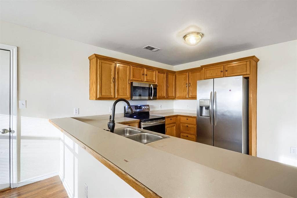 112 Sebastian Lane, Josephine, TX 75173 Kitchen featuring natural wood cabinetry, solid surface countertops, a stainless steel side-by-side refrigerator, built-in microwave, and a double-basin sink with a high-arch matte black faucet