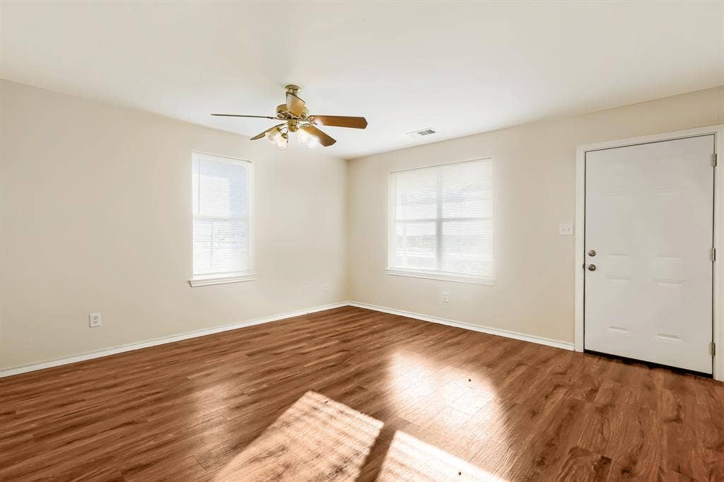 112 Sebastian Lane, Josephine, TX 75173 Interior space featuring laminate wood-finish flooring, neutral wall paint, two windows, and a ceiling fan with integrated lighting