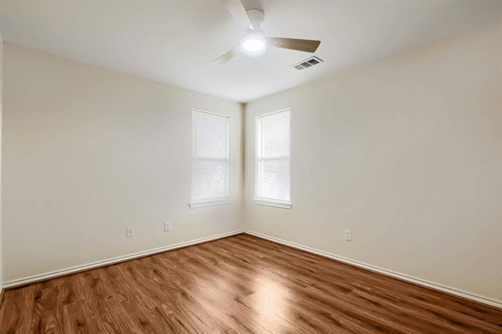 112 Sebastian Lane, Josephine, TX 75173 Neutral wall tones, wood-finish flooring, two windows with blinds, and a ceiling fan with integrated lighting