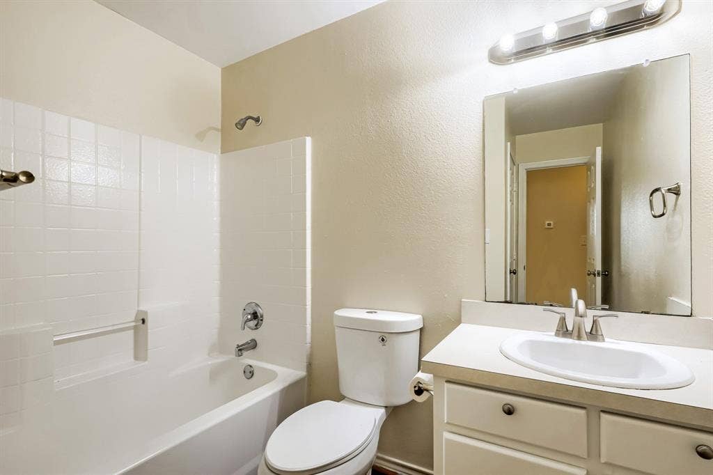 112 Sebastian Lane, Josephine, TX 75173 Bathroom featuring a vanity with an integrated basin, a white-tiled tub and shower enclosure, a rectangular wall-mounted mirror, and a multi-bulb vanity light fixture