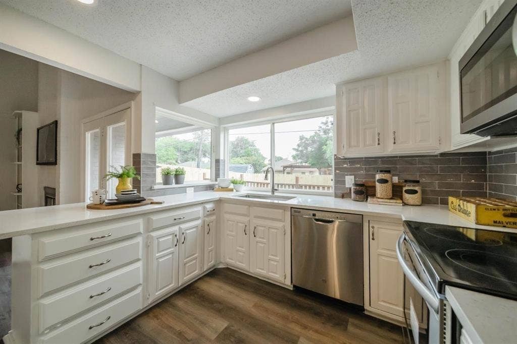 1903 Arvada Drive, Richardson, TX 75081 Kitchen featuring white cabinetry, solid-surface countertops, grey subway tile backsplash, stainless steel dishwasher, and wood-finish flooring