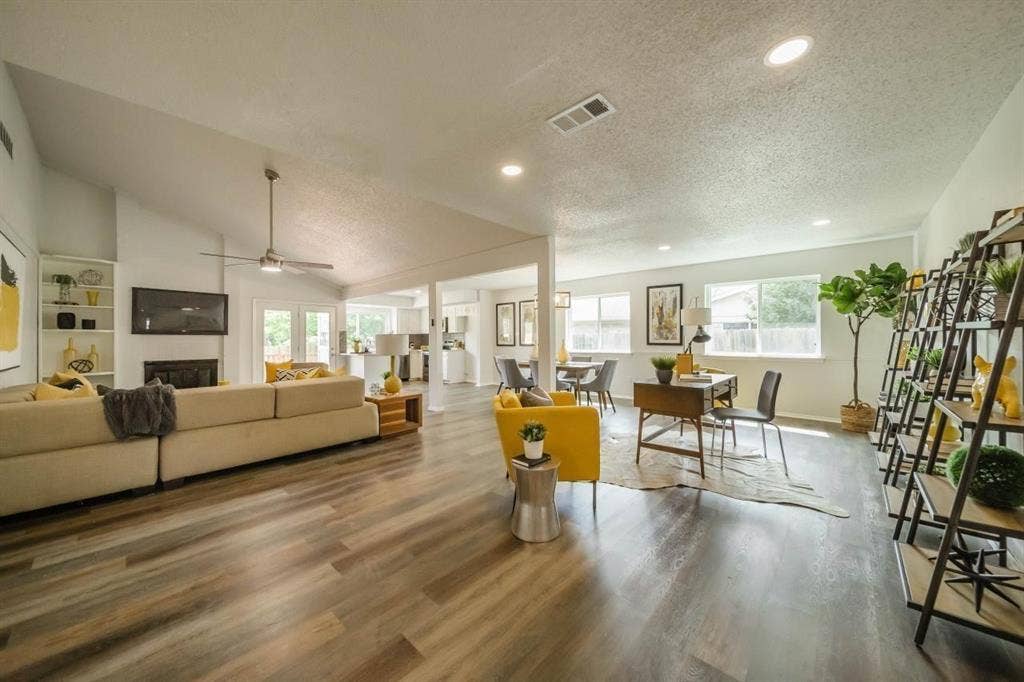 1903 Arvada Drive, Richardson, TX 75081 Open-concept interior featuring vaulted ceilings, wood-finish flooring, recessed lighting, a fireplace with built-in shelving, and multiple windows