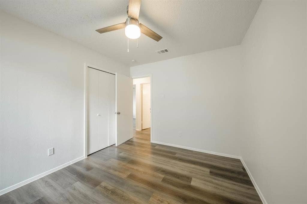 1903 Arvada Drive, Richardson, TX 75081 Room featuring wood-finish flooring, a ceiling-mounted light fixture with fan, and a closet with dual folding doors