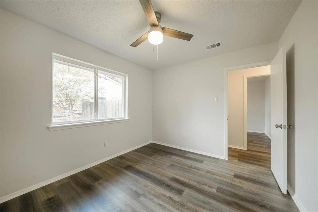1903 Arvada Drive, Richardson, TX 75081 Neutral-toned interior featuring wood-finish flooring, a ceiling fan with integrated lighting, and a large window