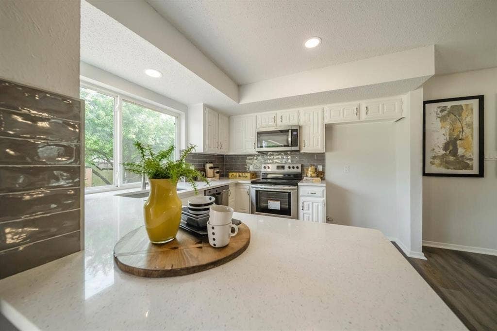 1903 Arvada Drive, Richardson, TX 75081 Kitchen featuring white cabinetry, quartz countertops, gray tile backsplash, stainless steel appliances, and recessed lighting