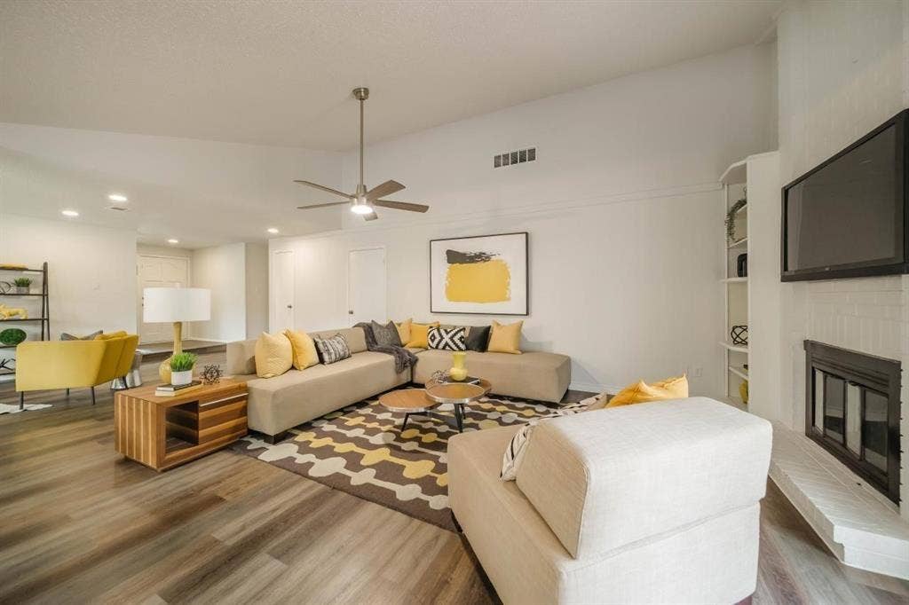 1903 Arvada Drive, Richardson, TX 75081 Living area featuring a vaulted ceiling, floor-to-ceiling painted brick fireplace, wood-finish flooring, ceiling fan, and built-in shelving