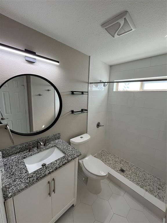 600 Royal Crest Drive, Richardson, TX 75081 Bathroom featuring a stone-composite countertop, white vanity cabinet with metallic hardware, circular wall-mounted mirror, and a walk-in shower with white tile surround and pebble-texture flooring