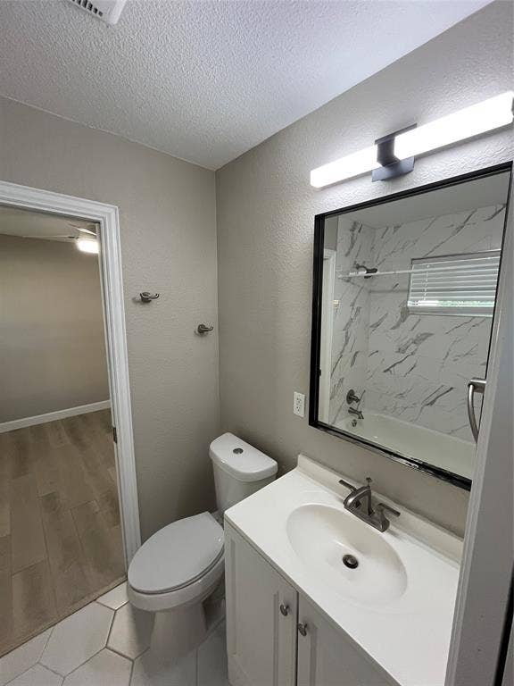 600 Royal Crest Drive, Richardson, TX 75081 Bathroom featuring a white vanity cabinet with a integrated sink, framed mirror, modern linear wall-mounted lighting, tub enclosure with decorative tile surround, and hexagonal tile flooring