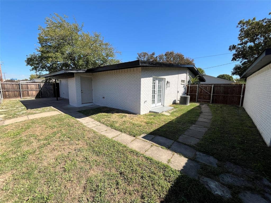 600 Royal Crest Drive, Richardson, TX 75081 White-painted brick exterior featuring a covered carport, stone paver walkways, and wood-fence perimeter