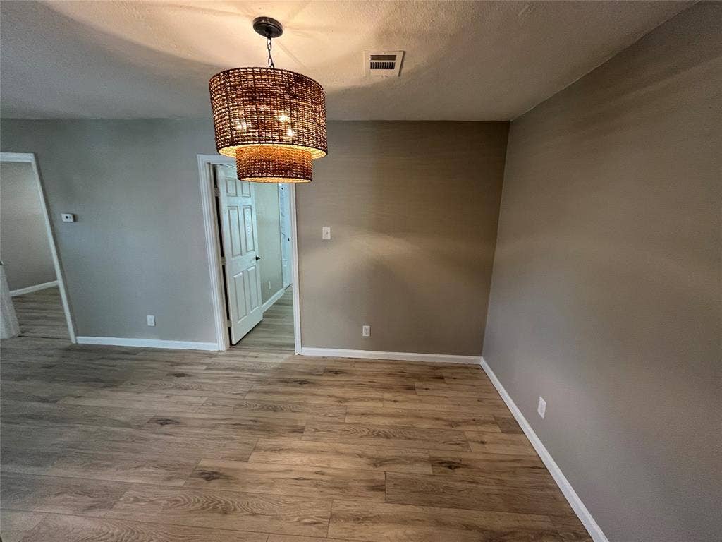 600 Royal Crest Drive, Richardson, TX 75081 Room featuring wood-finish flooring, neutral wall paint, and a tiered woven-texture drum pendant light