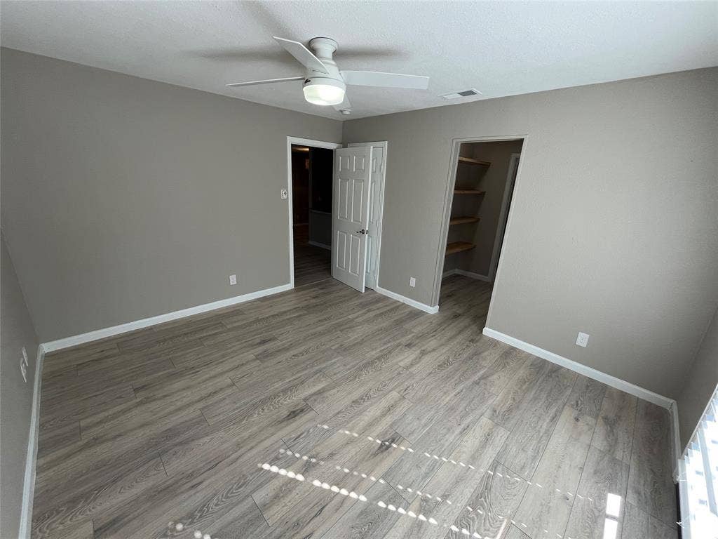 600 Royal Crest Drive, Richardson, TX 75081 Room featuring wood-finish flooring, a white ceiling fan with integrated lighting, and a walk-in closet with built-in shelving