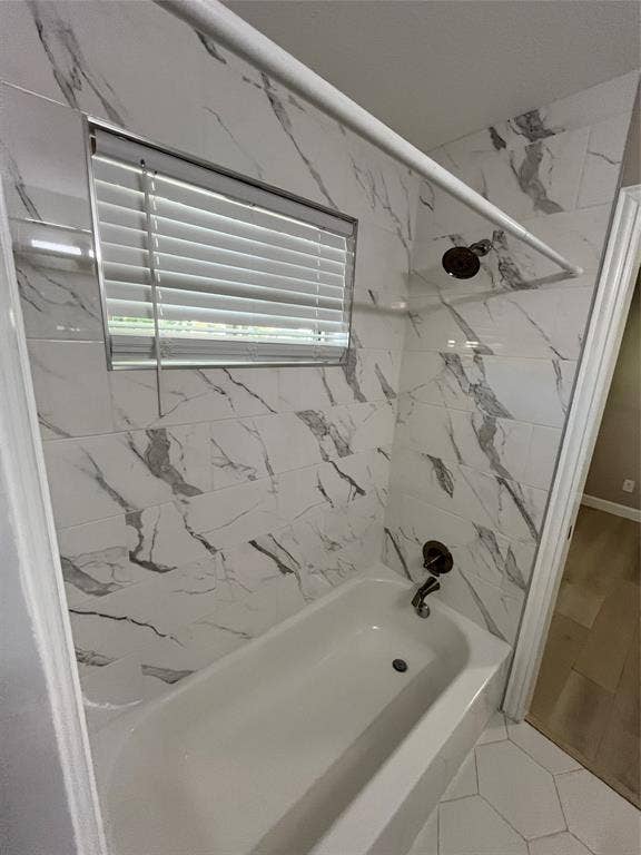 600 Royal Crest Drive, Richardson, TX 75081 Bathtub enclosure featuring large-format patterned tile walls, a built-in shower head, a bronze-finish faucet, and an integrated window with horizontal blinds