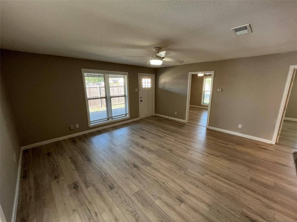 600 Royal Crest Drive, Richardson, TX 75081 Open-concept interior featuring wood-finish flooring, a multi-pane glass entry door, and a ceiling-mounted light fixture with integrated fan