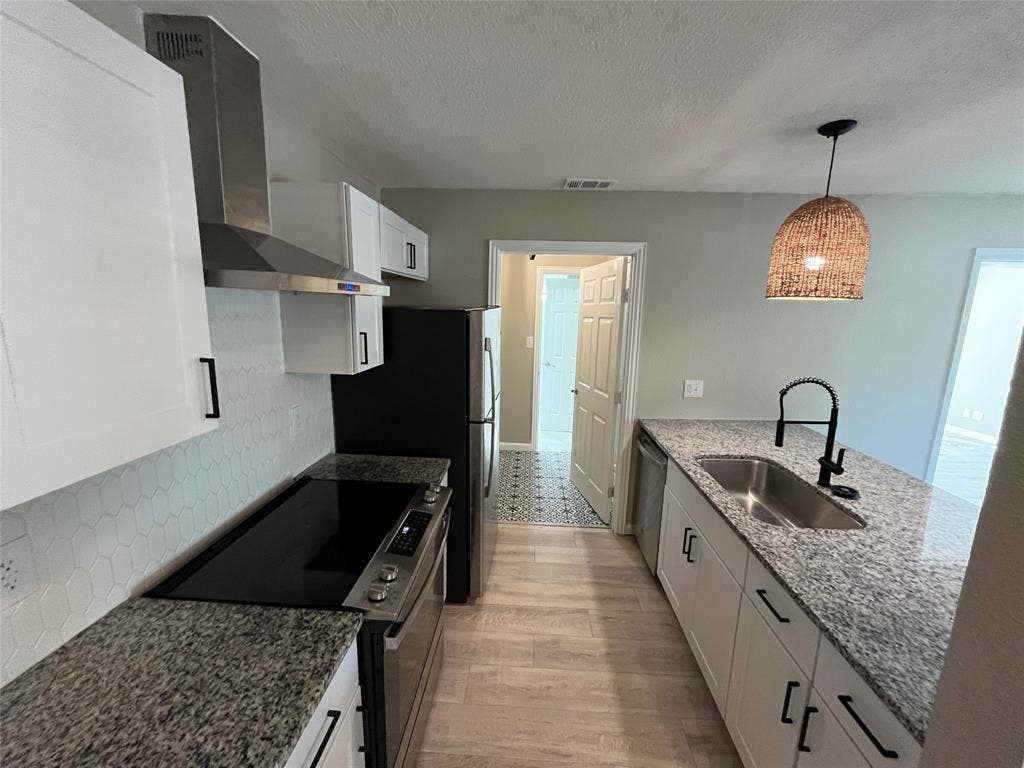 600 Royal Crest Drive, Richardson, TX 75081 Kitchen featuring shaker-style cabinetry, stone countertops, hexagonal tile backsplash, stainless steel range with overhead ventilation, and a gooseneck faucet