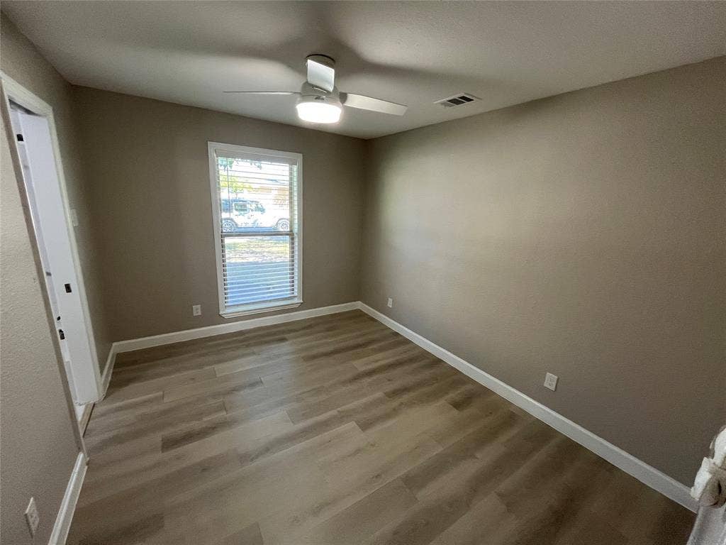 600 Royal Crest Drive, Richardson, TX 75081 Neutral-toned interior space featuring wood-finish flooring, a ceiling fan with integrated lighting, and a single-pane window with horizontal blinds