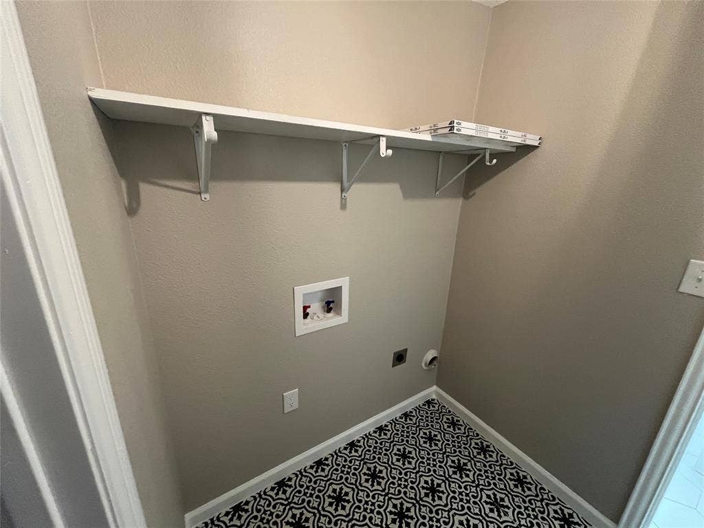 600 Royal Crest Drive, Richardson, TX 75081 Utility area featuring patterned ceramic tile flooring, a wall-mounted shelving unit with support brackets, and recessed plumbing hookups