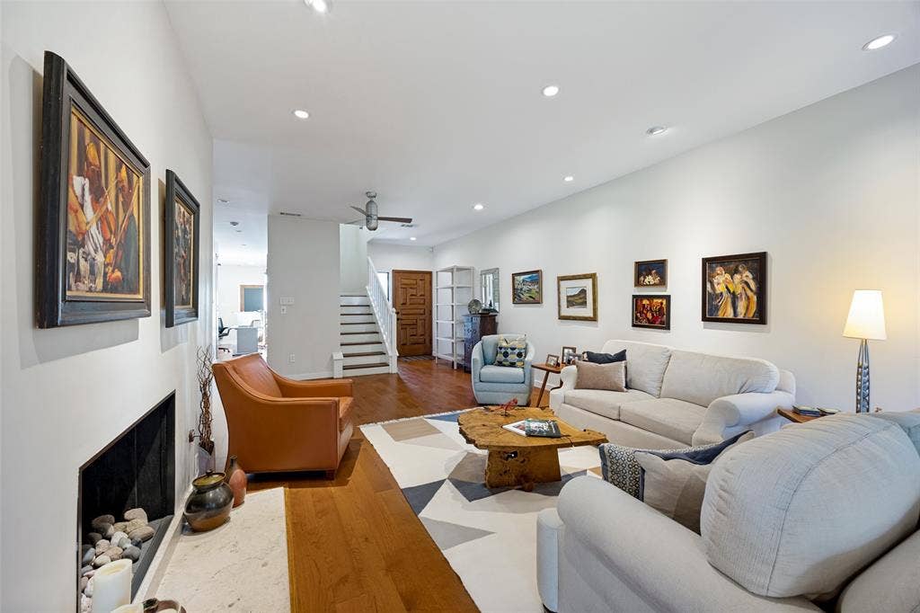 Living space featuring wood-finish flooring, recessed lighting, and a built-in fireplace with a stone hearth