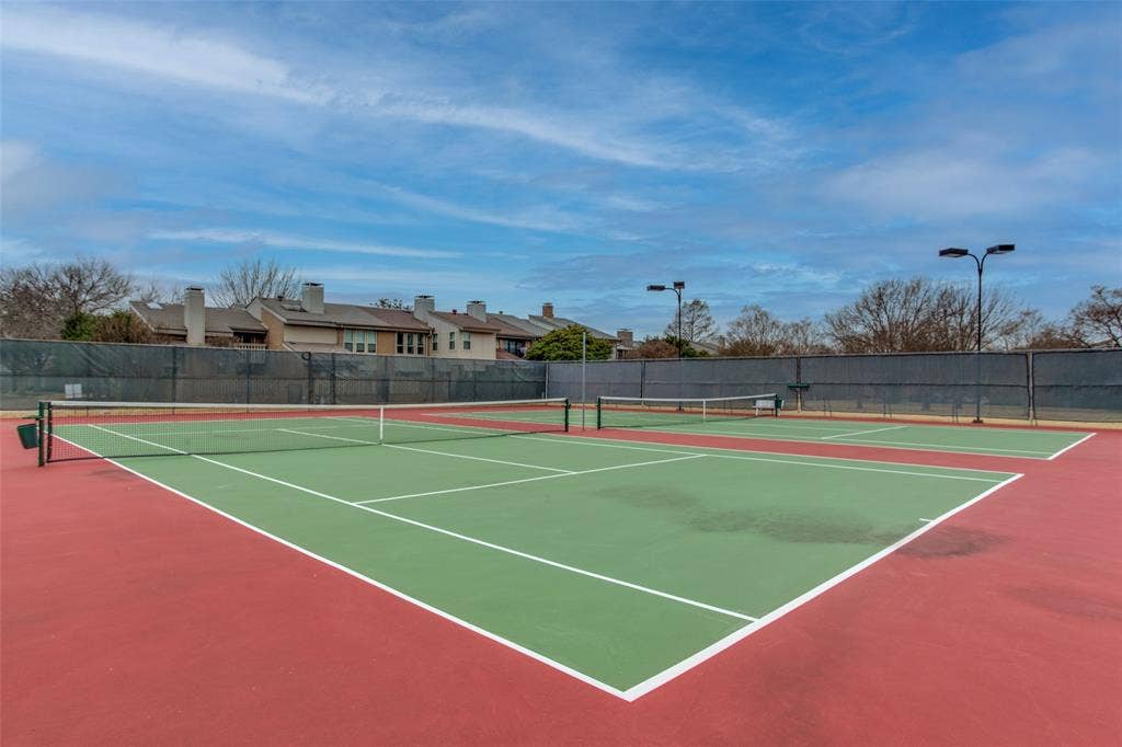 Dual hard-surface tennis courts featuring perimeter fencing and overhead court lighting