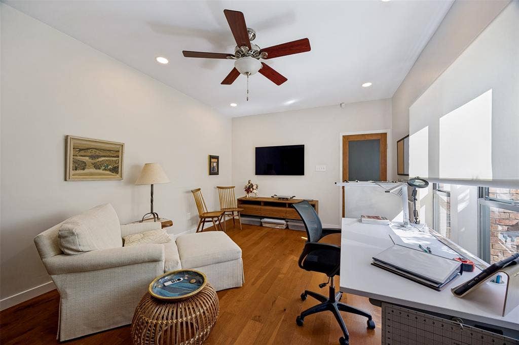 Room featuring wood-finish flooring, recessed lighting, ceiling fan, and large windows with roller shades
