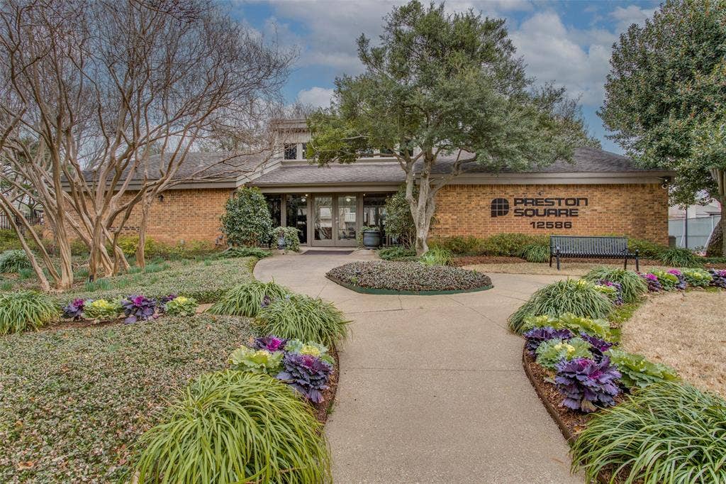 Single-story brick exterior featuring a multi-pane glass entrance, concrete walkway, and professionally manicured landscaping