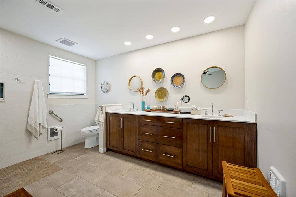Bathroom vanity with dark wood-finish cabinetry, dual undermount sinks, quartz countertop, and recessed ceiling lighting, complemented by tile flooring