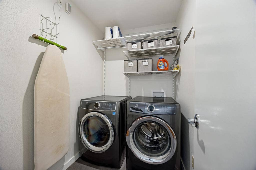 Laundry area featuring front-loading machines and integrated wire shelving