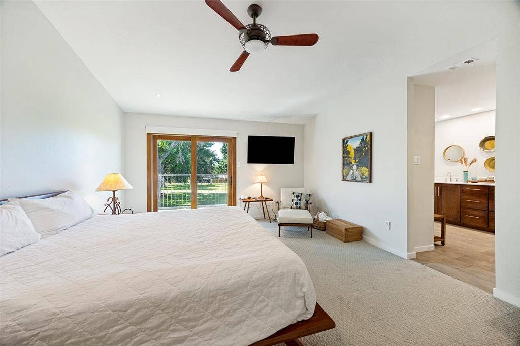 Bedroom featuring neutral wall-to-wall carpeting, ceiling fan with integrated lighting, and sliding glass doors with exterior access