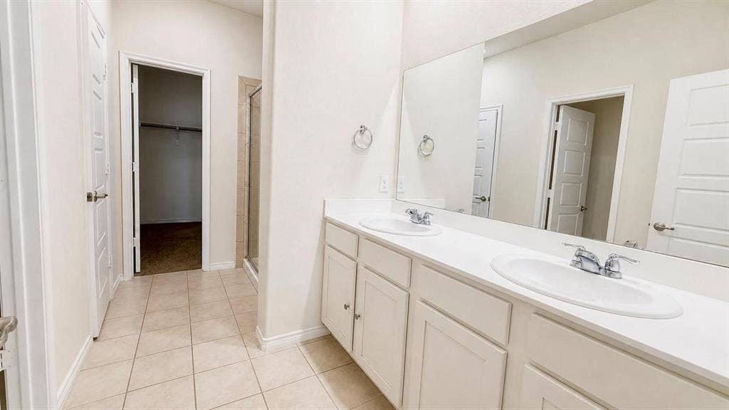 Primary ensuite bathroom with dual vanities and walk-in closet