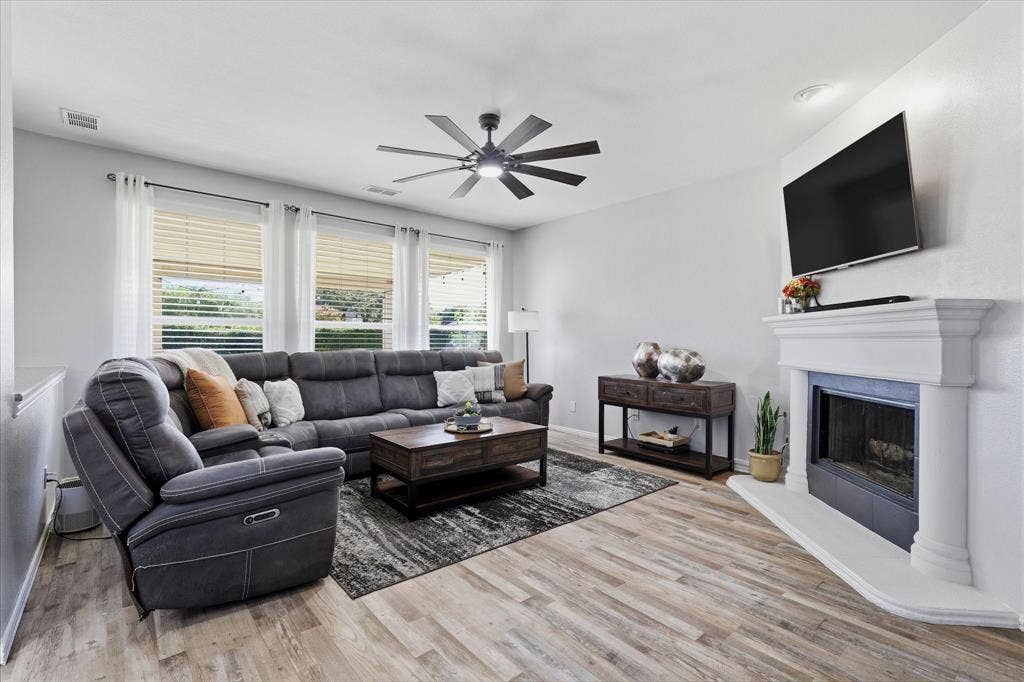 A fireplace with a crisp white mantel anchors the family room, where generous windows draw the outdoor setting inside.