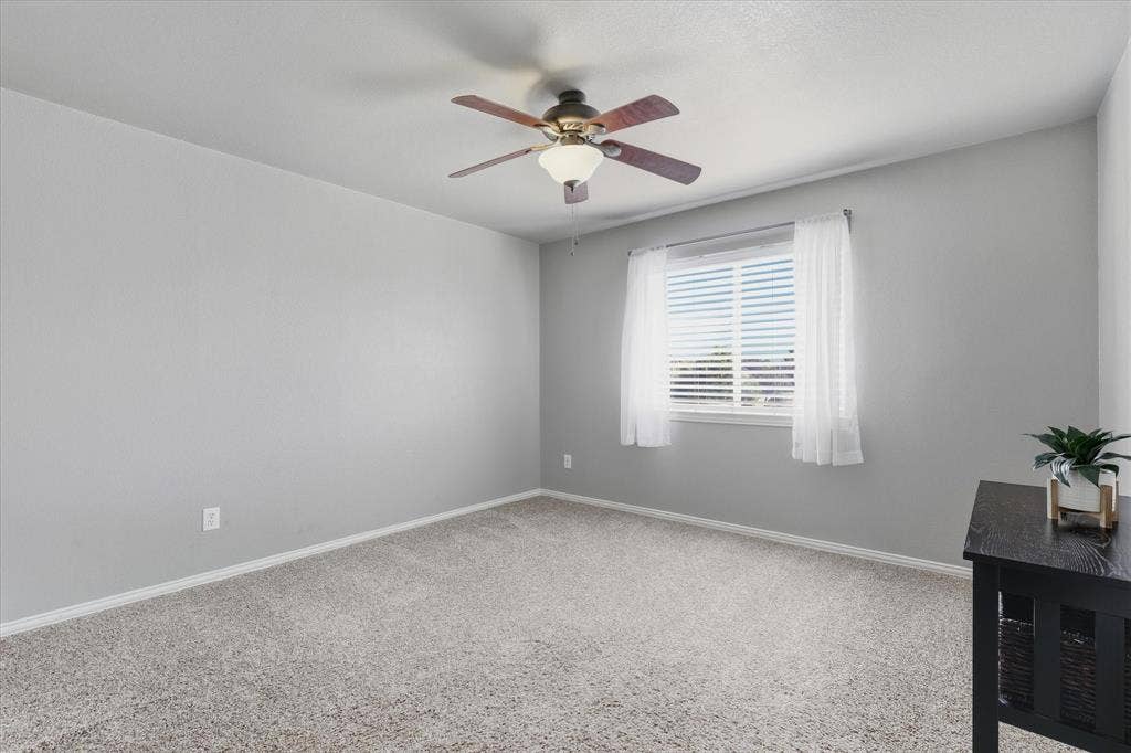 An upstairs secondary bedroom features a neutral palette, carpeting & natural light.
