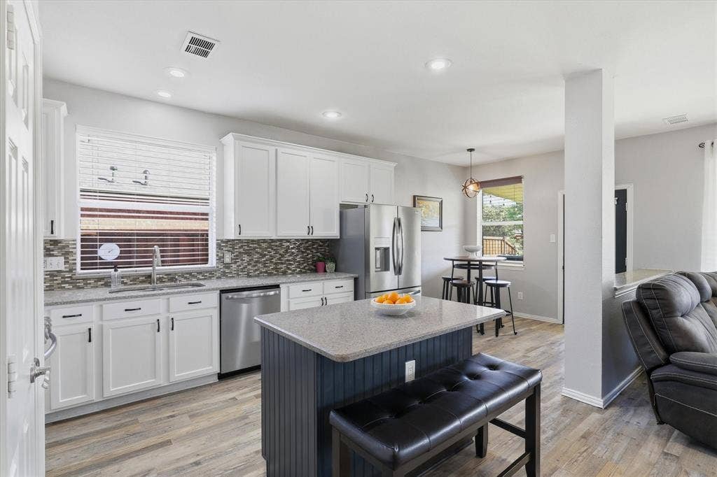 The expanded kitchen pairs classic white cabinetry with a contrasting navy island, adding storage, seating & generous space for meal preparation.