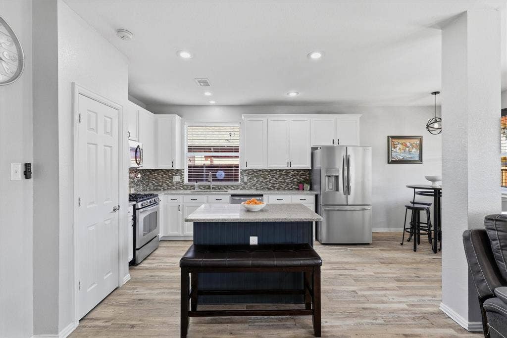 Updated countertops, a mosaic backsplash, decorative lighting & stainless-steel appliances, including a gas range, complete the space.