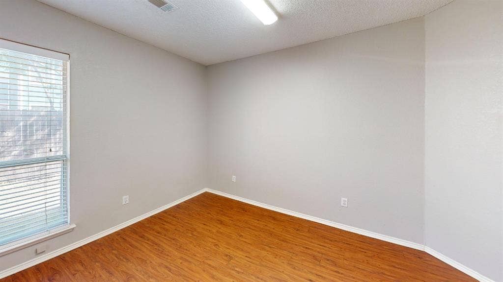 5210 Welbeck Court, Garland, TX 75043 Neutral-toned walls, wood-finish flooring, and single-pane window with horizontal blinds