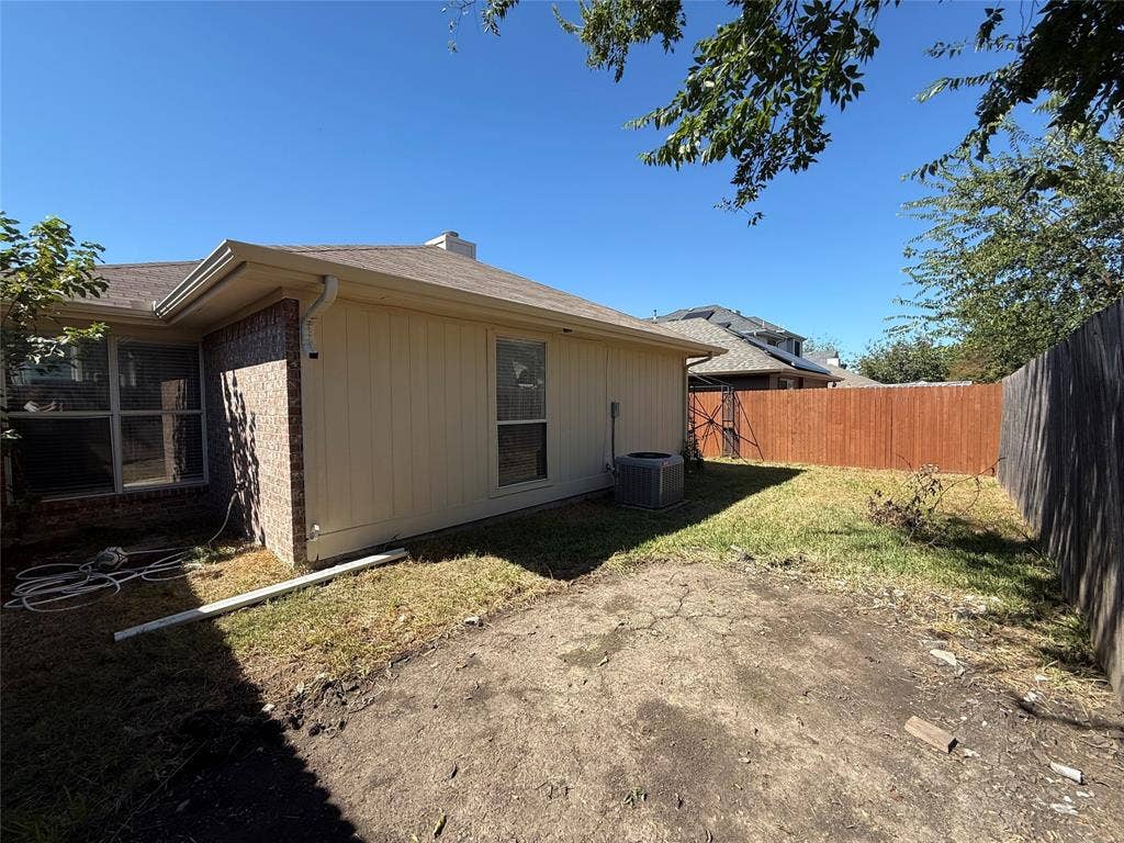 5210 Welbeck Court, Garland, TX 75043 Rear exterior featuring a brick and panel siding facade, grass yard, and wood privacy fencing