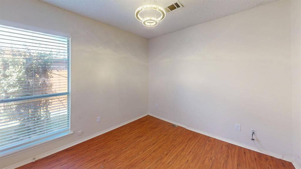 5210 Welbeck Court, Garland, TX 75043 Room featuring wood-finish flooring, a contemporary circular pendant light fixture, and horizontal slat window blinds