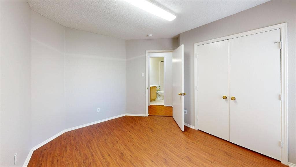 5210 Welbeck Court, Garland, TX 75043 Wood-finish flooring, neutral wall tones, double-door reach-in closet, and flush-mount overhead lighting