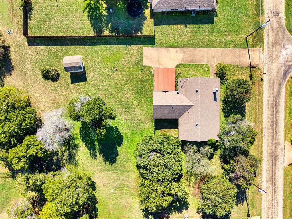 Aerial perspective of a sprawling lot featuring mature trees, a detached storage structure, and a concrete driveway