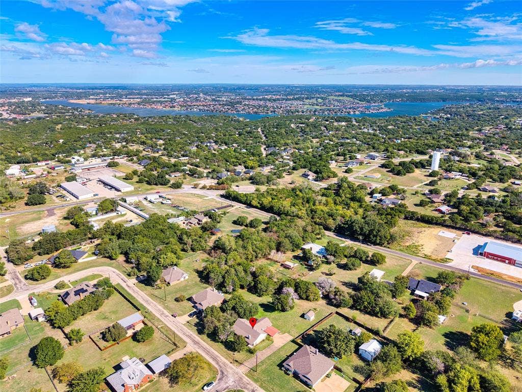 Aerial perspective of a residential lot featuring mature trees and proximity to a large body of water