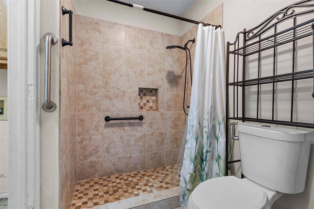 Walk-in shower featuring neutral tile walls, a mosaic tile floor, an integrated wall niche, and oil-rubbed bronze hardware