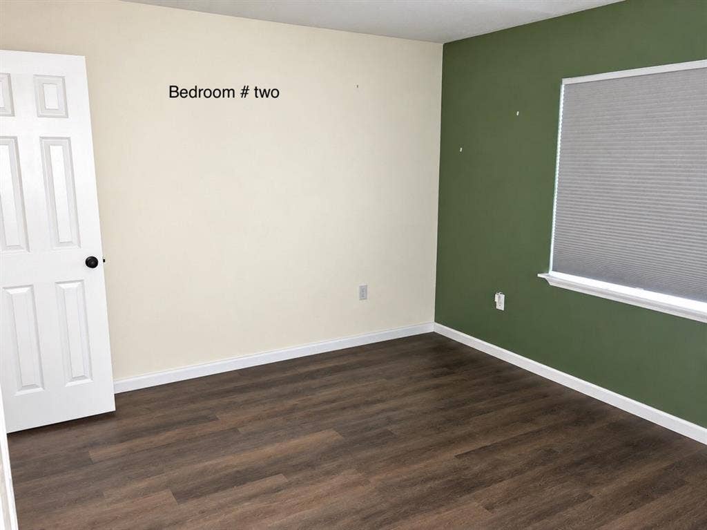 709 SW Dallas Street, Grand Prairie, TX 75051 Room featuring wood-finish flooring, a six-panel door, and a cellular shade window treatment