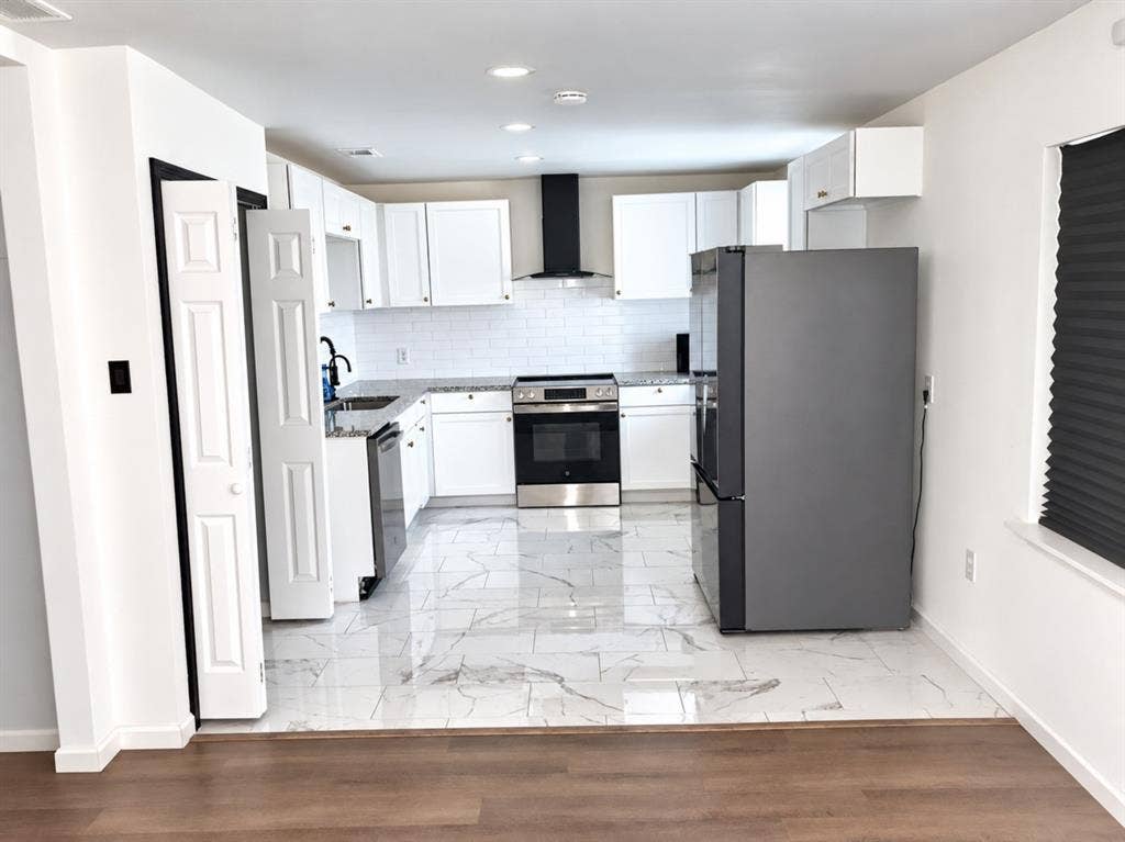 709 SW Dallas Street, Grand Prairie, TX 75051 Kitchen featuring white Shaker-style cabinetry, stone-finish countertops, white subway tile backsplash, stainless steel appliances, and large-format rectified tile flooring