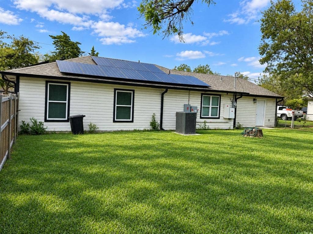 709 SW Dallas Street, Grand Prairie, TX 75051 Exterior featuring white siding, roof-mounted solar panels, an asphalt shingle roof, and a fenced backyard
