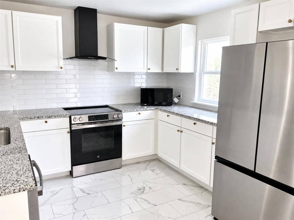 709 SW Dallas Street, Grand Prairie, TX 75051 Kitchen featuring white shaker-style cabinetry, speckled stone countertops, white subway tile backsplash, stainless steel appliances, and large-format porcelain tile flooring