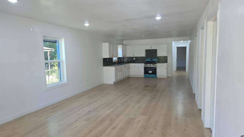 3426 Edgewood Street, Dallas, TX 75215 Open-concept interior featuring light-tone wood-finish flooring, recessed lighting, white cabinetry, dark tiled backsplash, and built-in appliances