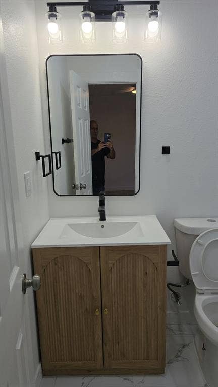 3426 Edgewood Street, Dallas, TX 75215 Vanity featuring a light wood-finish cabinet with arched panel doors, a white countertop, and a matte black faucet