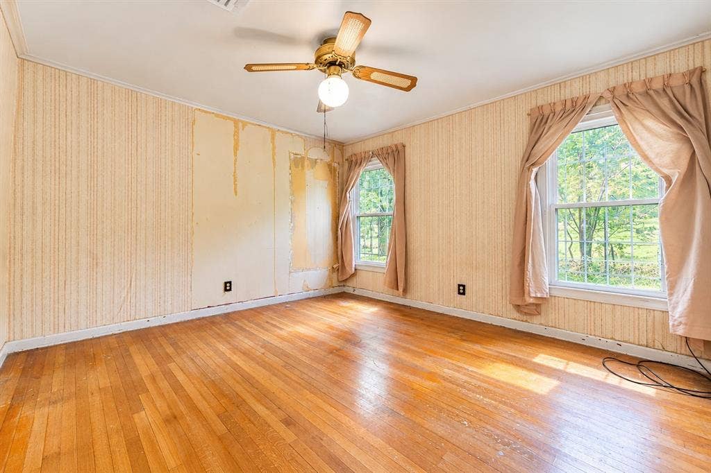 Wood-finish flooring, dual windows with grid muntins, and a ceiling-mounted fan with integrated lighting